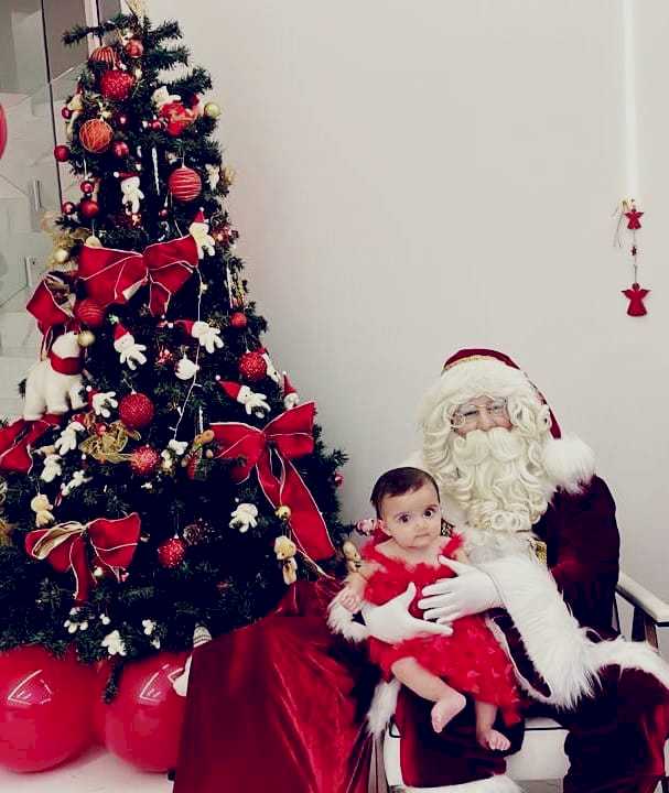 Papai noel posando com um bebe para uma foto em Santana de Parnaiba